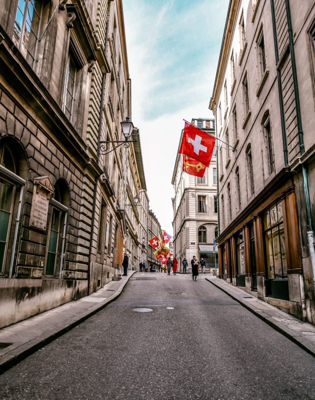 Beautiful Idyllic Street With Architecture And Flags In Geneva, Switzerland Beautiful Idyllic Street With Architecture And Flags In Geneva, Switzerland